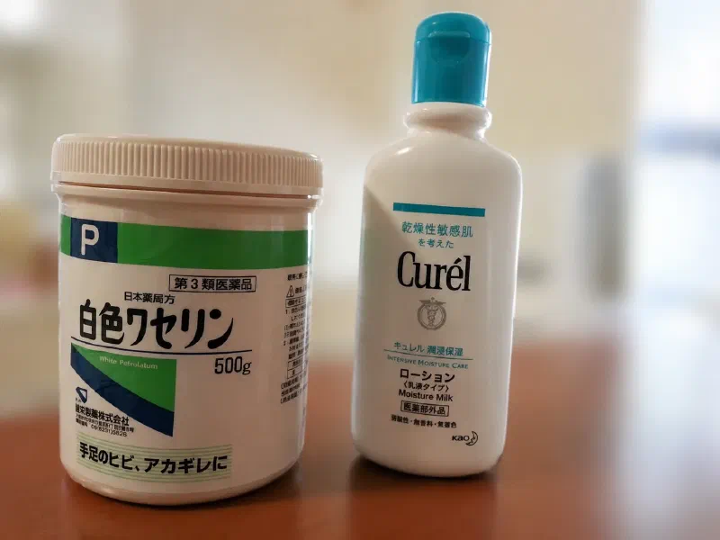 キュレルローションと白色ワセリンを並べた写真。指先の保湿ケアに使用している2アイテム